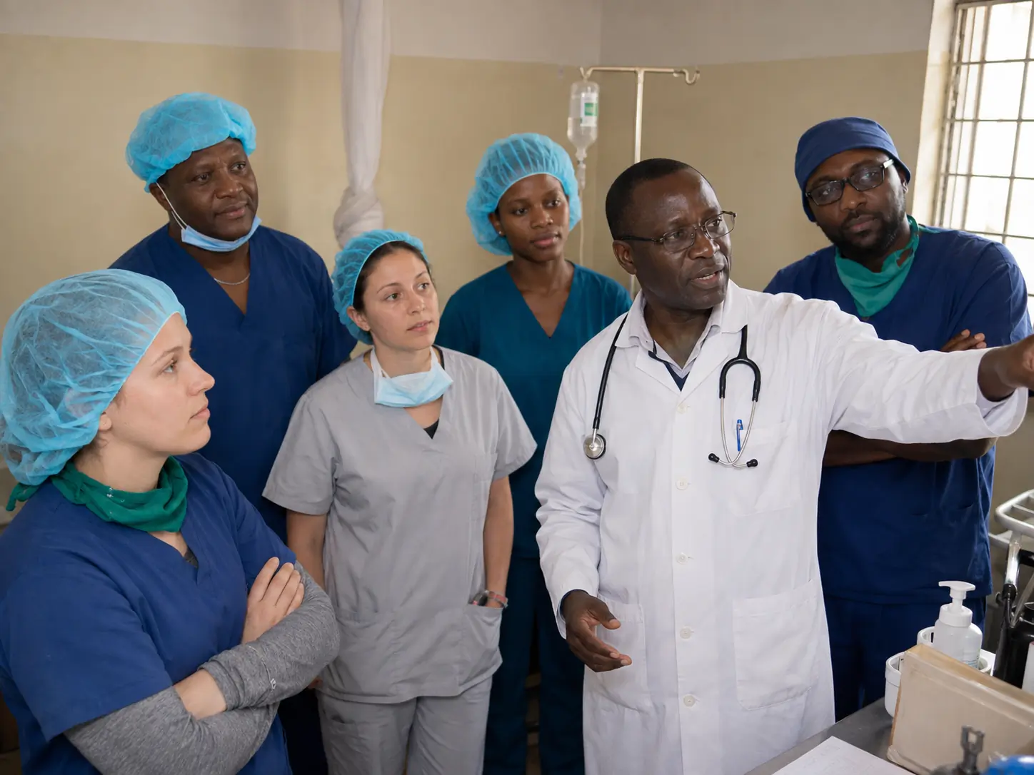 Tanzanian doctor leading a clinical discussion with healthcare professionals and international elective students.